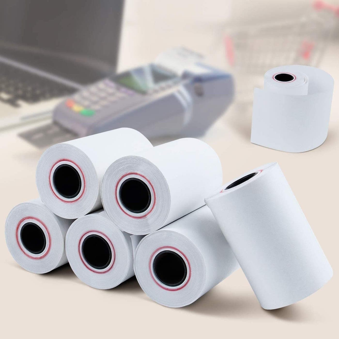 Stack of white thermal till rolls beside a card machine
